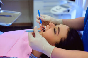 Dentist examining female’s teeth in dentistry.