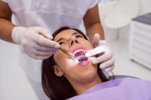 Close up of dentist examining Patient teeth with a mouth mirror