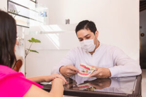 Dentist explaining the procedure with an artificial denture to h