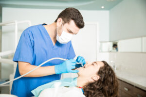 Woman Receiving Dental Treatment From Dentist In Clinic